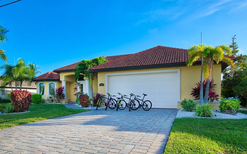 Front exterior of the home with a paver driveway, two-car garage, and bicycles available for guest use
