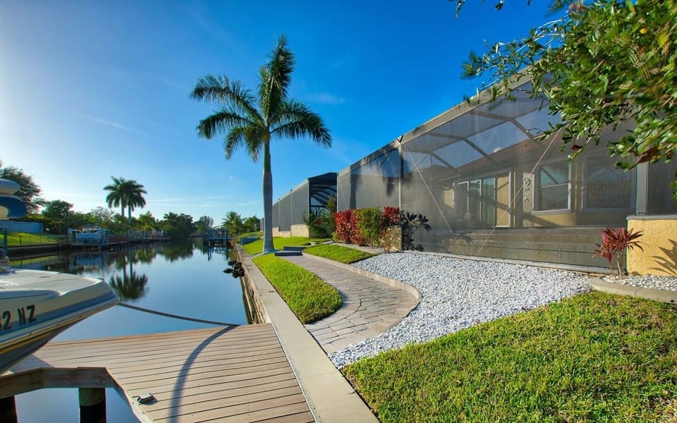 Rear yard showing the curved pool, dock, and direct access to the canal waterway beyond