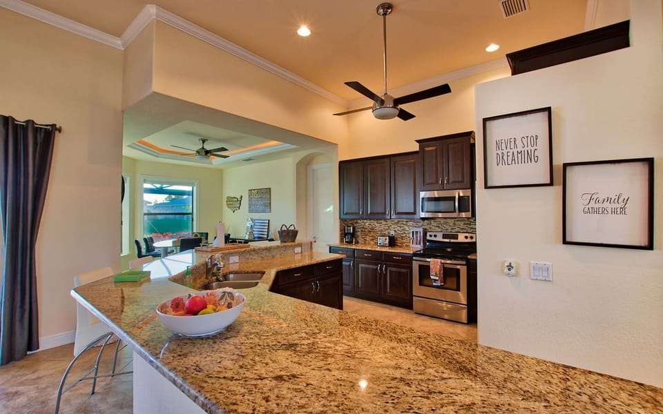Gourmet kitchen with dark wood cabinets, granite countertops, stainless steel appliances, and tile backsplash