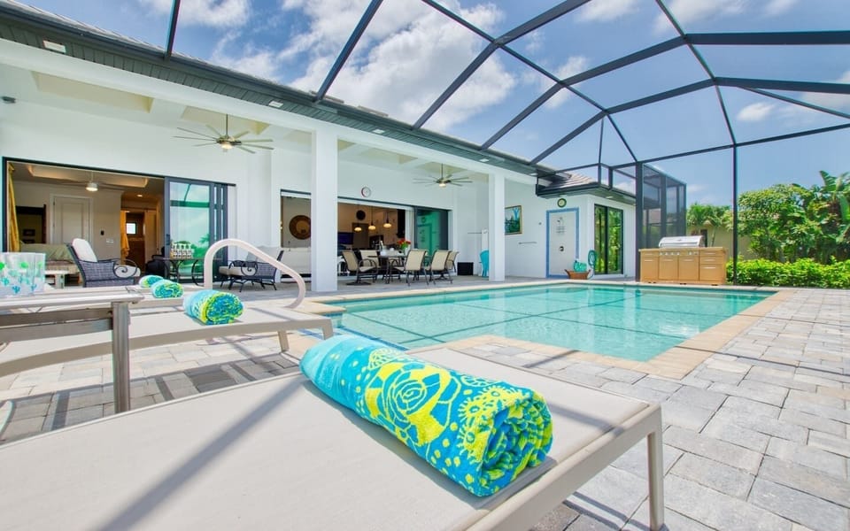 Pool and screened cage with lounge chairs and the home exterior in the background