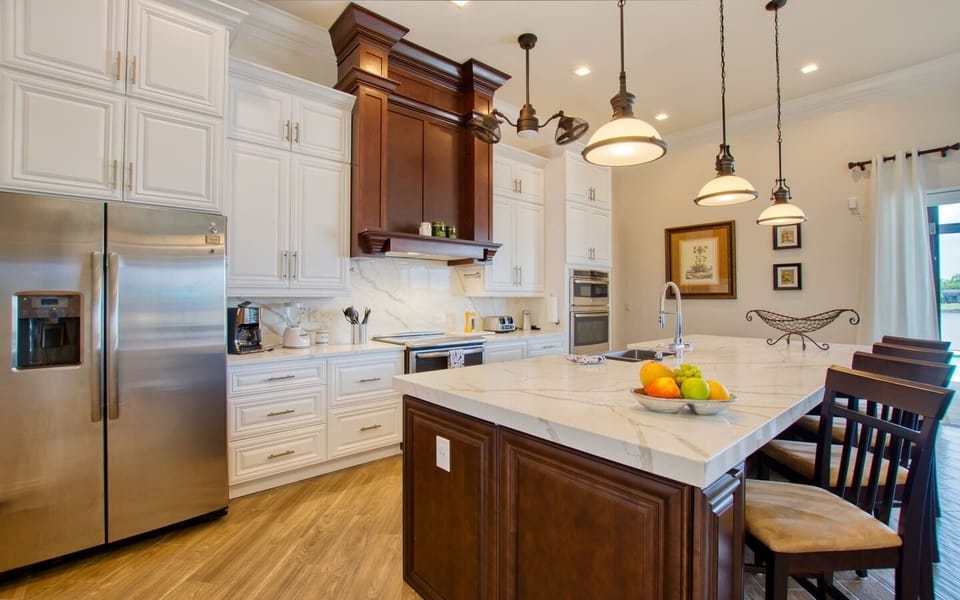 Kitchen with dark wood cabinetry, large granite island, and stainless steel appliances