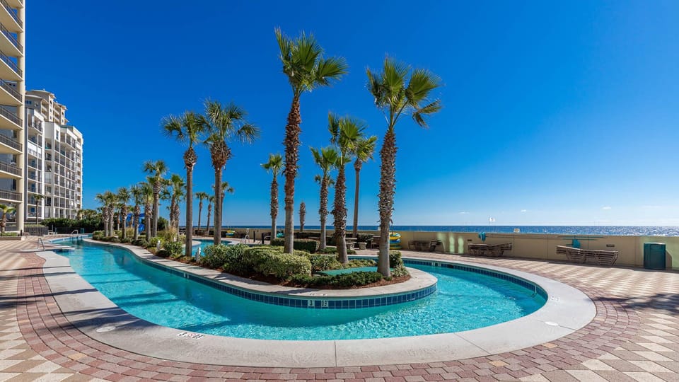 Relax by the sparkling lazy river surrounded by palm trees, with stunning views just steps from the beach at Phoenix West
