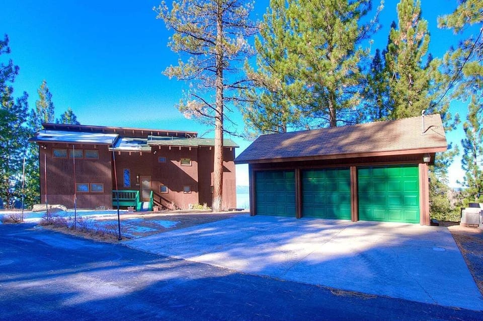 Front exterior with trees, lake glimpse, stairs, and house exterior.