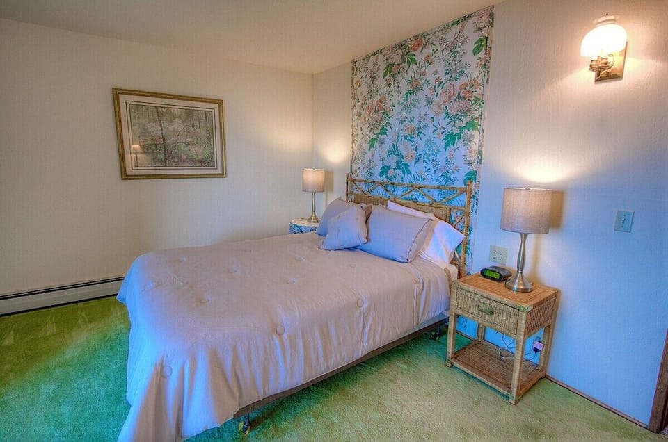 Another look at the bedroom, with nightstands, wall art, bed, and lamps.