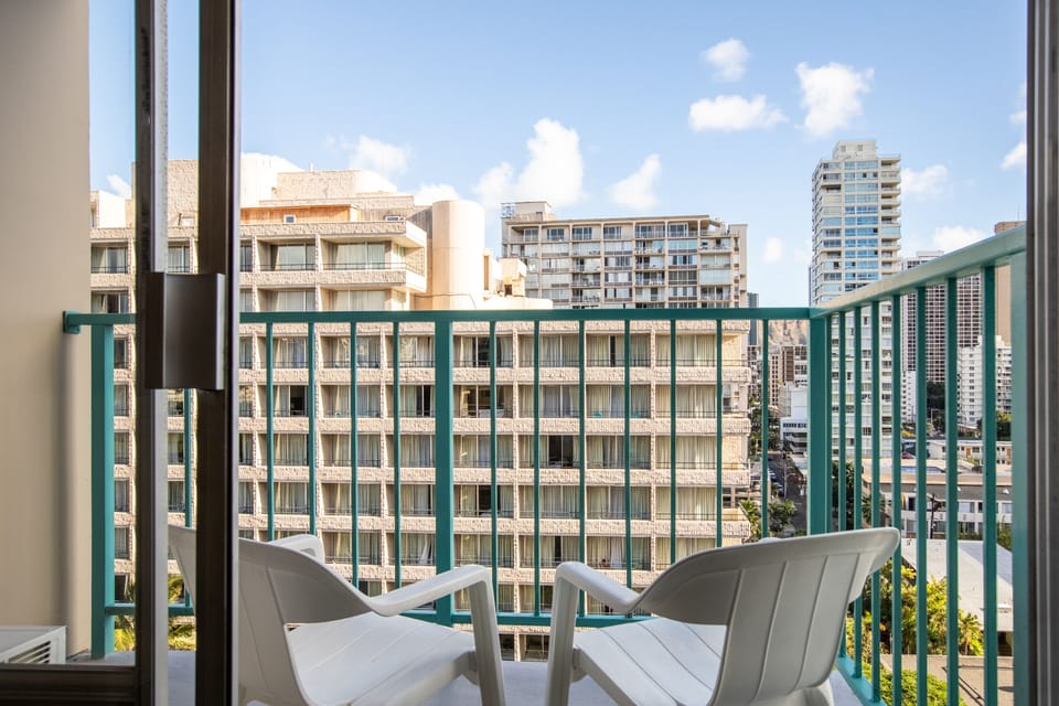 A private balcony showcasing the surrounding cityscape, featuring nearby buildings and a clear blue sky—your perfect spot to enjoy morning coffee while taking in the urban atmosphere.