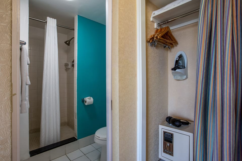Your bright bathroom features a fully tiled walk-in shower with fresh towels waiting. Convenient built-in storage and a handy iron nook keep everything you need right where you'll need it.