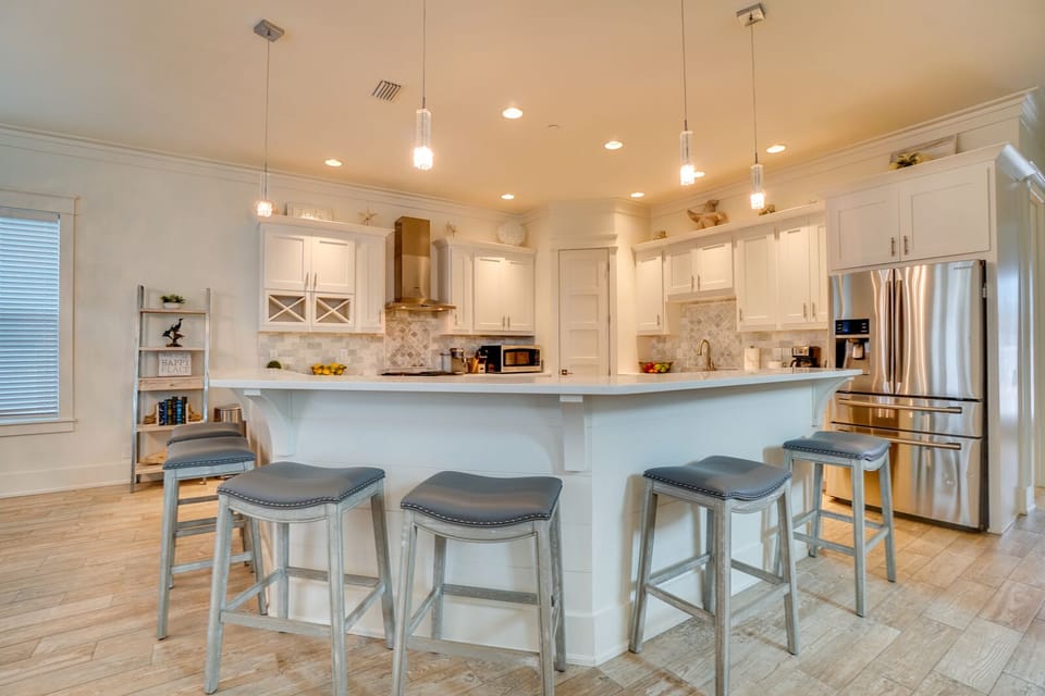 Step into your fully equipped kitchen where crisp white cabinets and elegant pendant lighting create the perfect space for preparing memorable meals.