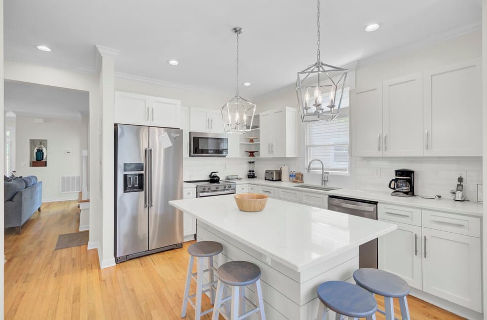 Step into your bright, modern kitchen featuring pristine white countertops, stainless steel appliances, and elegant pendant lighting perfect for cooking and gathering.
