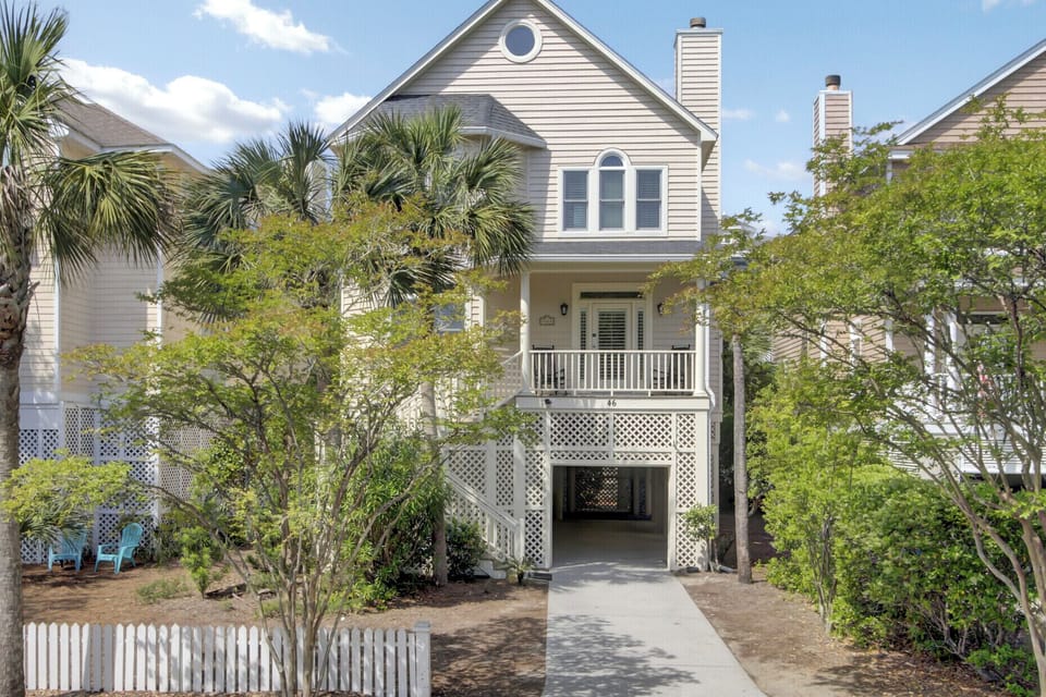 Charming coastal cottage with front porch and tropical landscaping, nestled in a peaceful residential neighborhood.