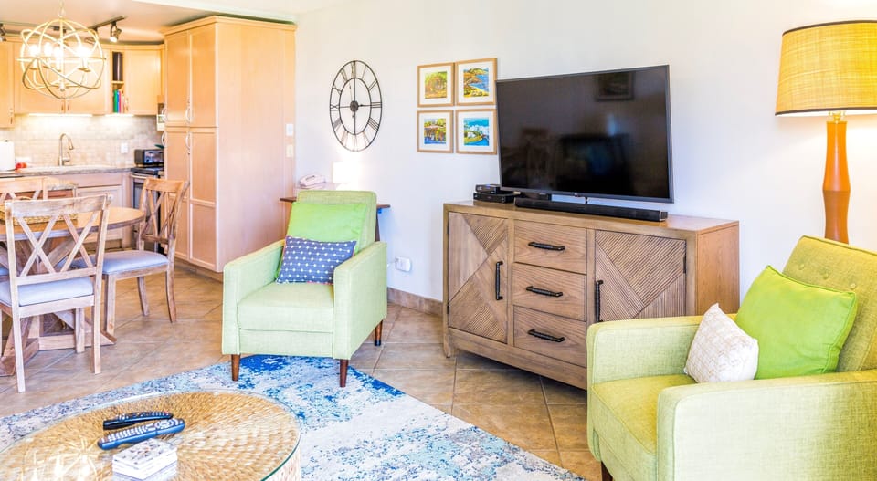 Living room features ocean view, large TV with ceiling fan and A/C.