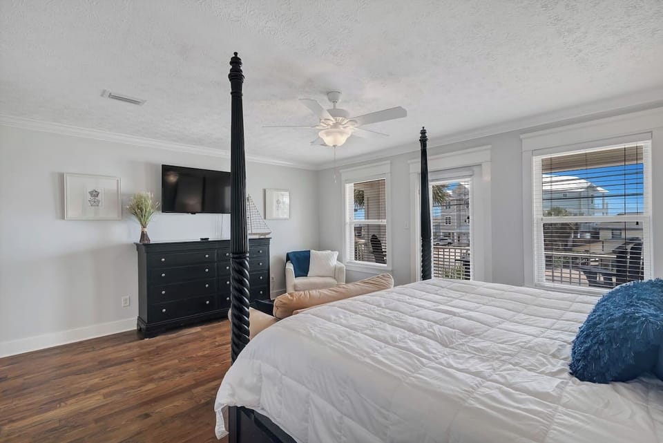 The bedroom has a ceiling fan, mounted smart TV, large closet, and tabletop fan.