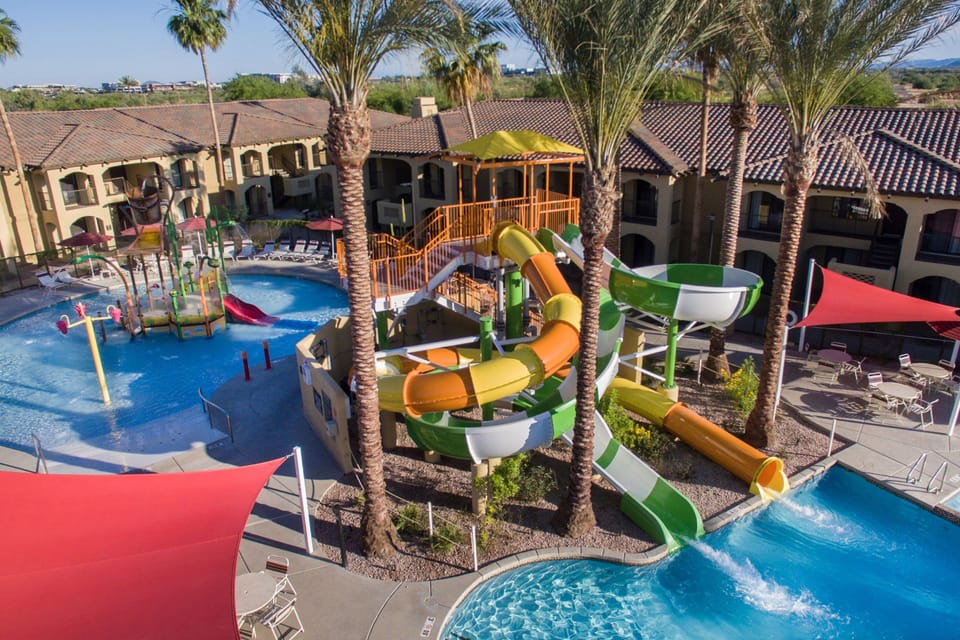 Experience excitement with twists and turns on colorful water slides surrounded by palm trees and sunshine.