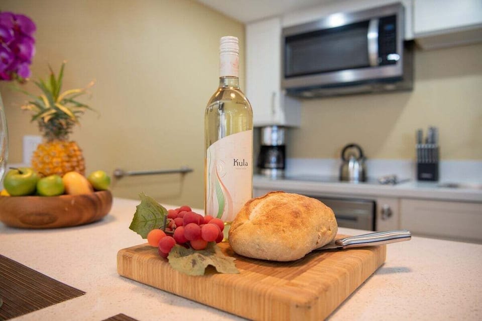 Kitchen counter styled with wine, bread, grapes, and pineapple — a welcoming touch of island indulgence.