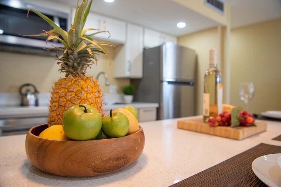Kitchen counter with tropical fruit bowl, wine glasses, and strawberries, setting the stage for island flavors.