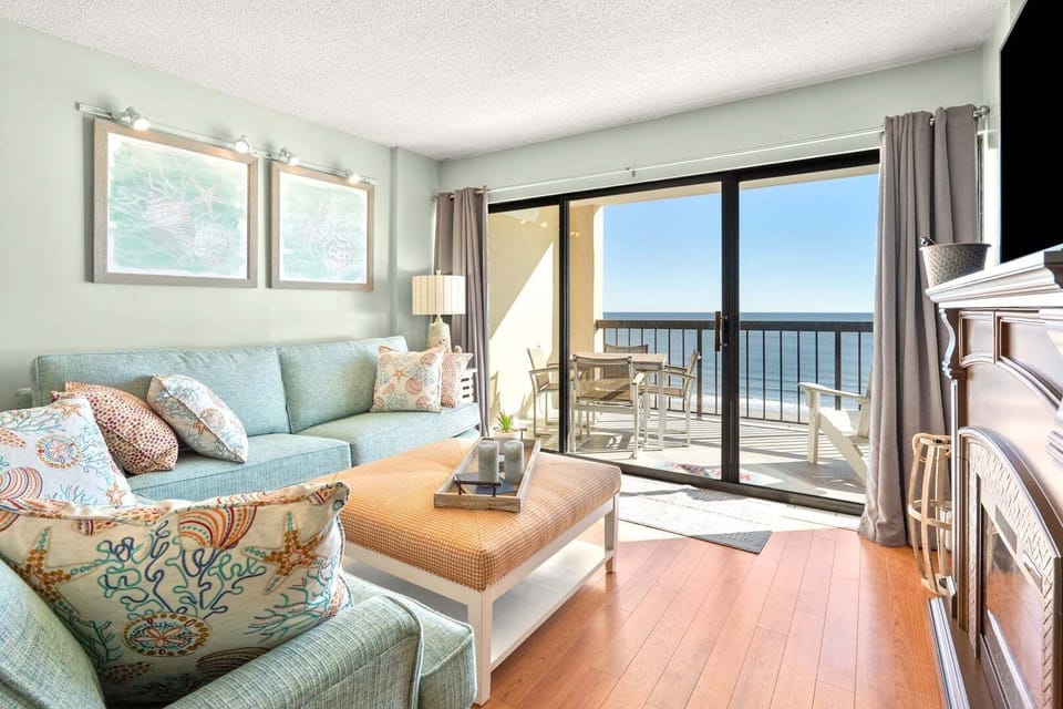 Ocean-view living area with sliding doors to the balcony at Crescent Towers II 707, a 3-bedroom Crescent Beach rental
