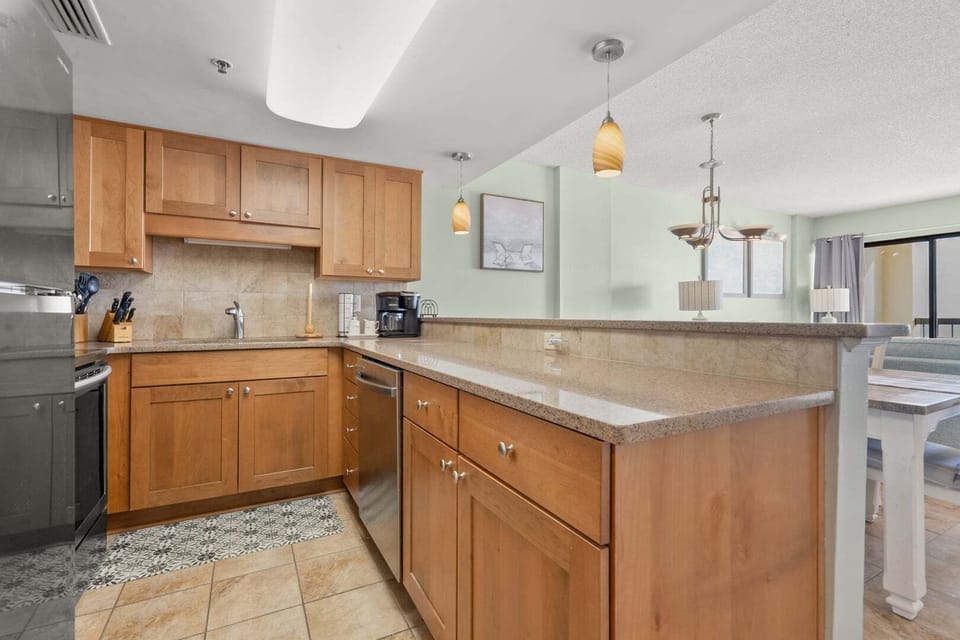 Light-toned cabinetry and an island with bar seating at Crescent Towers II 707, a Crescent Beach vacation rental