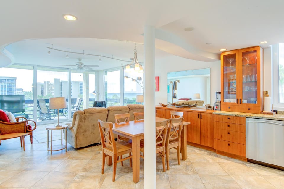 Wood dining table with four chairs is positioned beside warm wood cabinetry topped with granite in the kitchen area.