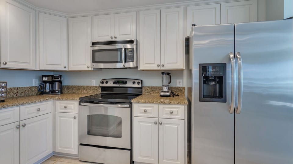 White cabinetry, granite countertops, and stainless steel appliances create a clean, timeless look.