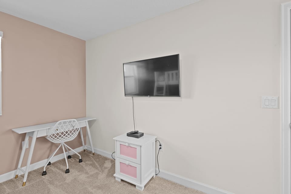 Your dedicated workspace features a modern desk and comfortable chair, while the wall-mounted TV adds entertainment after productive days.