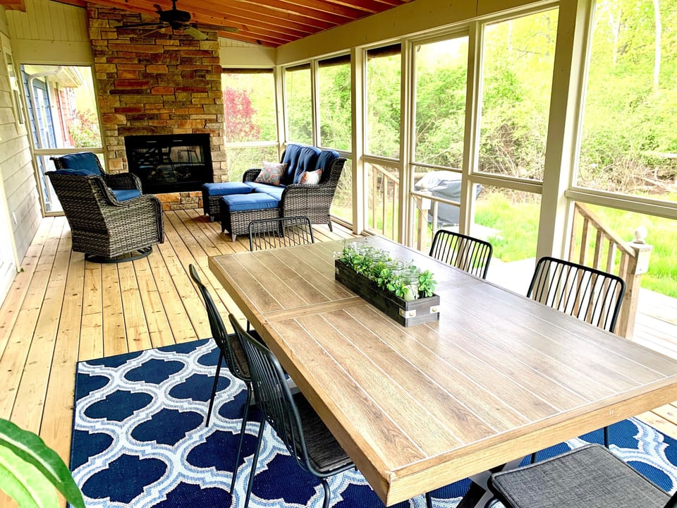 Oversized screened in porch with couch, two rockers and dining table.