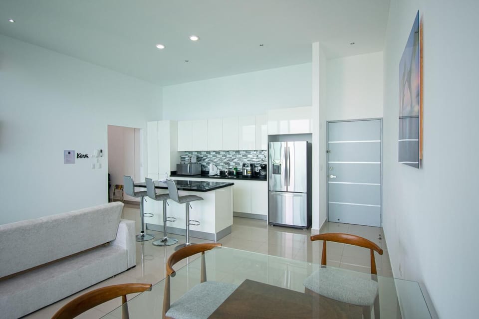 Glossy white cabinets and a black granite island contrast with sleek stainless steel appliances in the kitchen area.