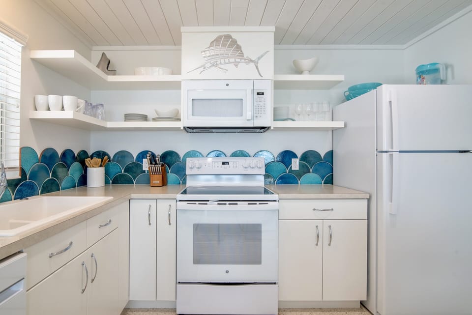 White cottage kitchen with open shelving and fully stocked.