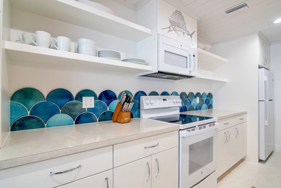 Watercolored handmade, hand glazed terra cotta tiles are the focal point of this fully stocked cottage kitchen.