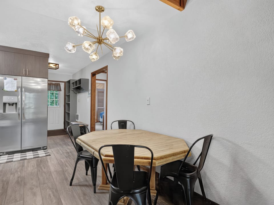 Gather around this stylish dining table under a striking modern chandelier—your meals here will feel both cozy and elegant, with the kitchen just steps away.