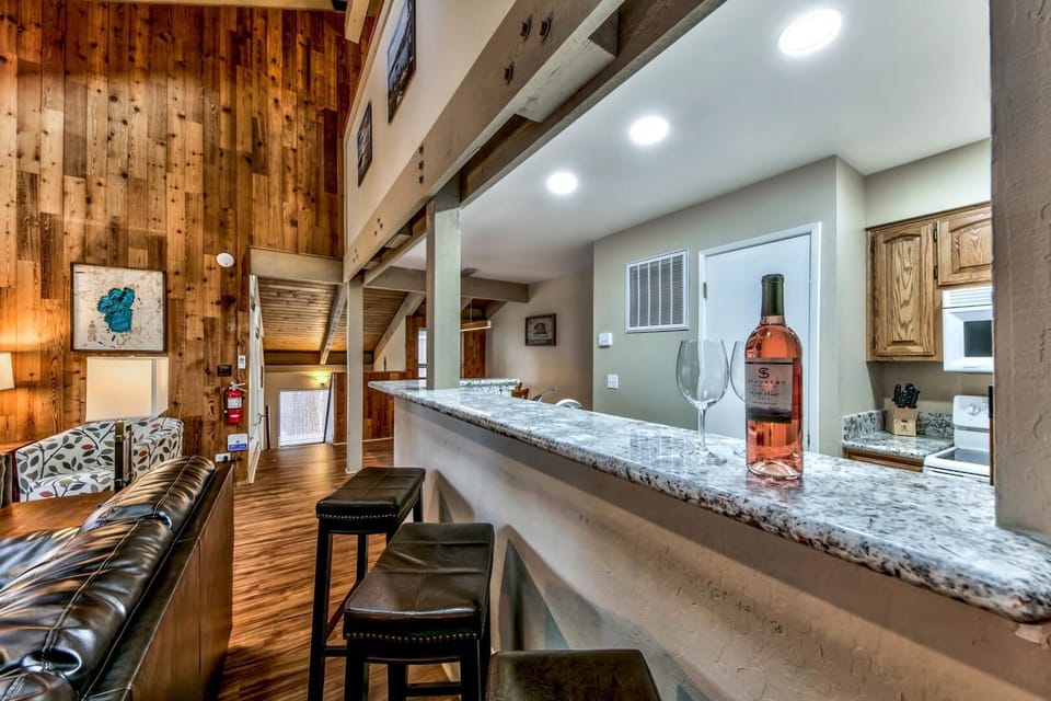 Unwind with a glass of wine at the kitchen counter with studded leather barstool seating for 3. Note: the living room furniture has been updated since this photo was taken.