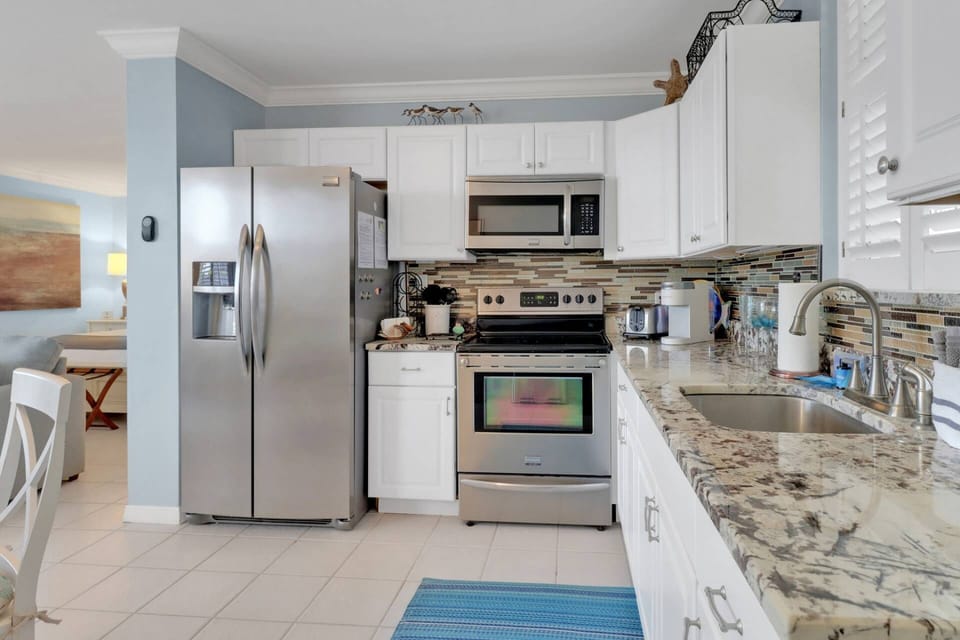 The kitchen is appointed with stainless steel appliances, quartz counters, tile backsplash, and farmhouse sink.