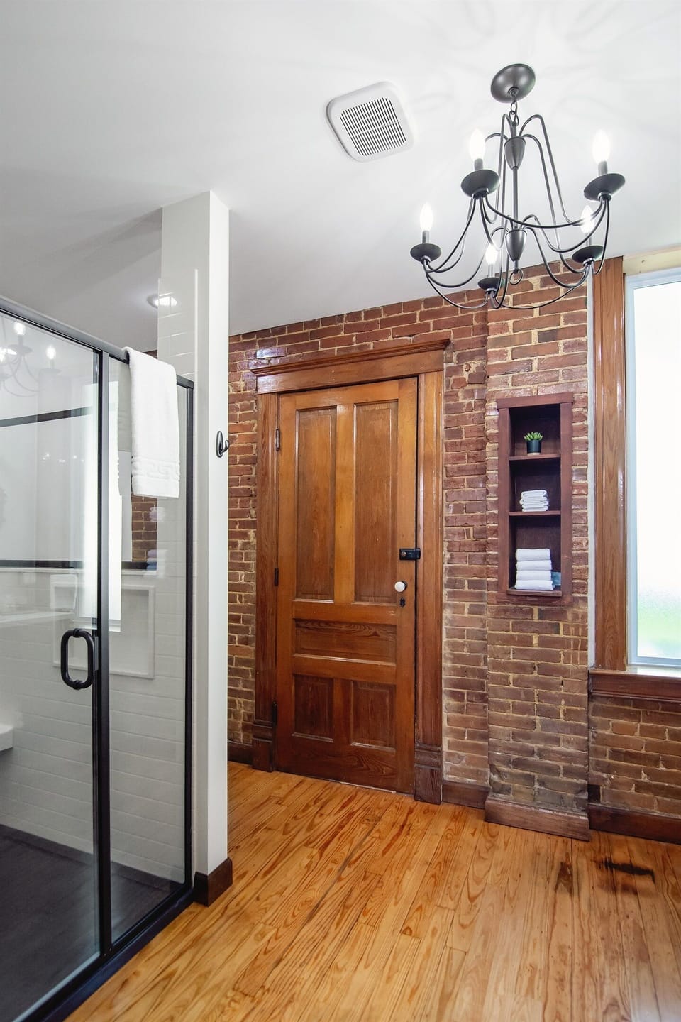 Spacious stand up shower with bench, grab bars, and hand held shower head.
