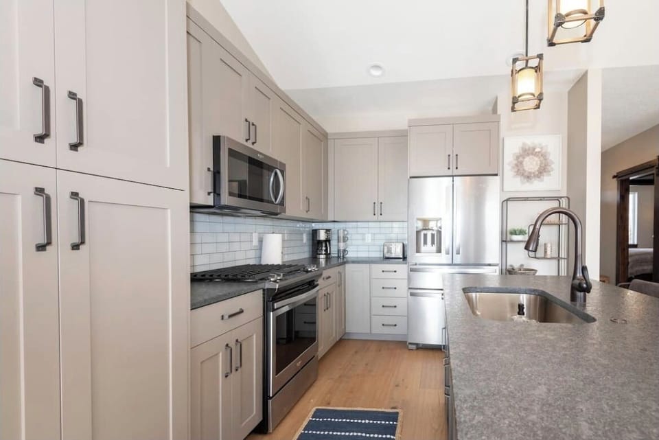 The gourmet kitchen features an island with seating for three and is equipped with stainless steel appliances, including a microwave, gas stove, and spacious refrigerator.