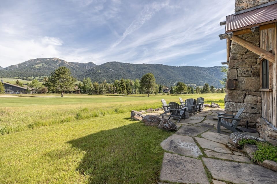 Mountain retreat with stone patio, fire pit seating, and sweeping views of forested peaks and open meadows.