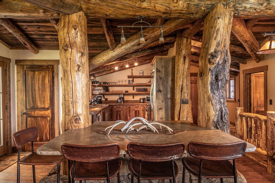 Gather around this stunning handcrafted table beneath soaring timber beams that tell stories of rustic elegance. Your mountain retreat kitchen awaits, blending natural charm with modern comforts.
