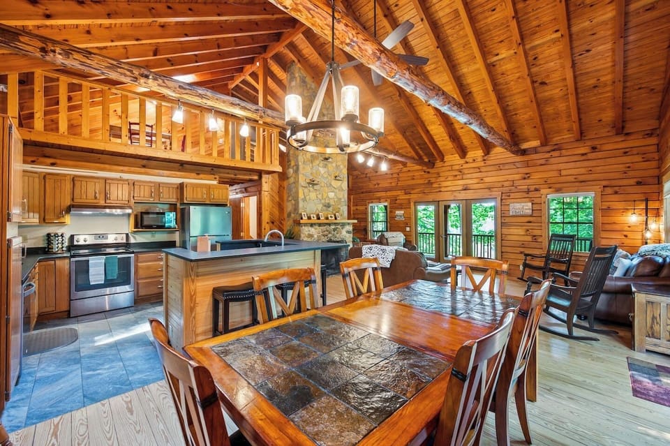 This enormous great room with soaring , wood burning fireplace is totally open with lots of seating, fully stocked kitchen and slate topped dining table with seating up to ten. 