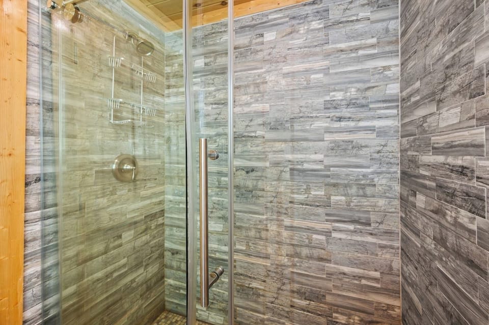 Refresh in this sleek glass shower enclosure with beautiful stacked stone tile in warm neutrals. Single handle shower control. Unwind and recharge!
