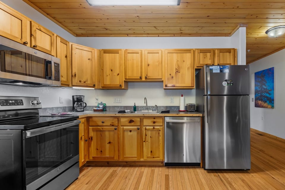 Your fully equipped kitchen features warm knotty pine cabinetry, stainless steel appliances, and everything you need to prepare meals during your mountain retreat.