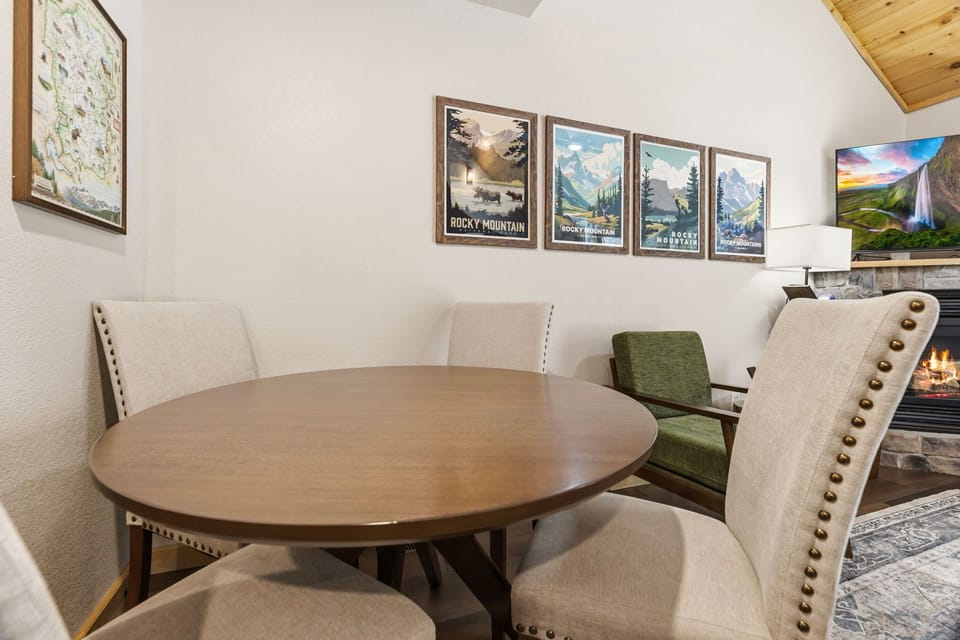 Gather around your private dining table, where mountain artwork inspires conversation and the cozy fireplace creates perfect ambiance for memorable meals together.