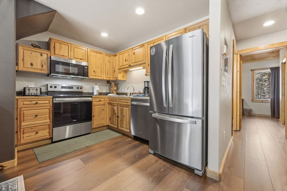 Cook delicious meals in your fully equipped kitchen featuring stainless steel appliances, warm wood cabinets, and modern countertops.