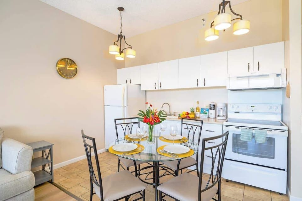 Modern kitchen and dining area with a glass table set for four and white appliances.