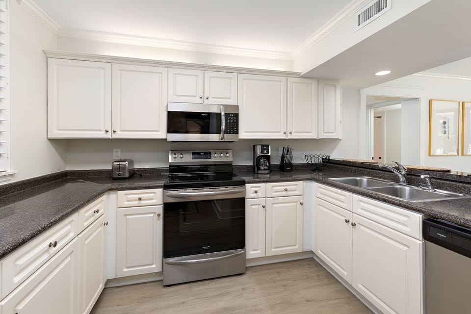 The open Kitchen has stainless steel appliances and crisp, white cabinets.