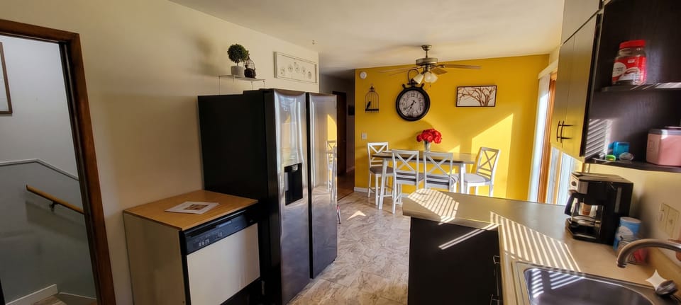 Bold yellow dining area w/ farmhouse table & stainless fridge — so fun!