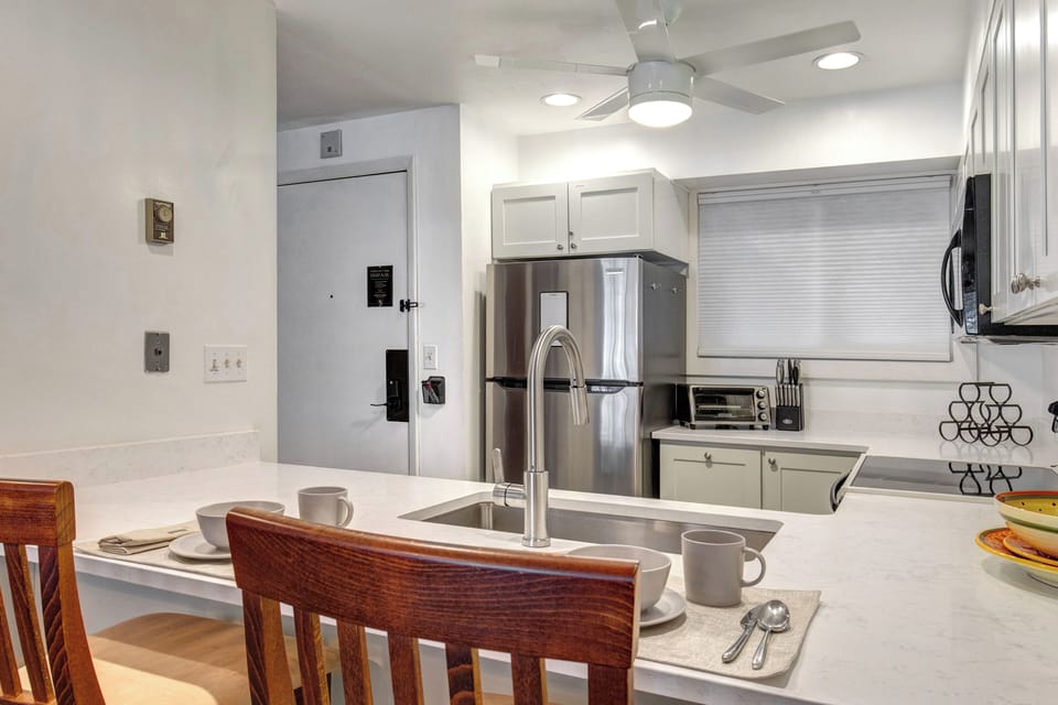 The kitchen offers a breakfast bar with seating for two guests and stainless steel appliances.