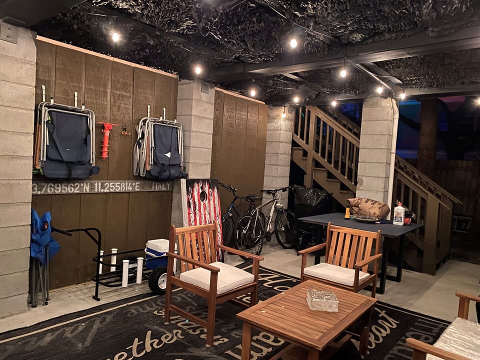 Ground level underneath home with seating, bikes and beach items