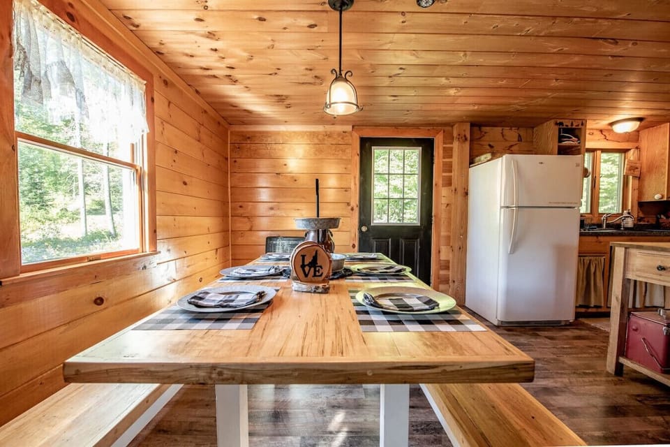 Rustic dining area surrounded by windows for natural light and mountain ambiance.