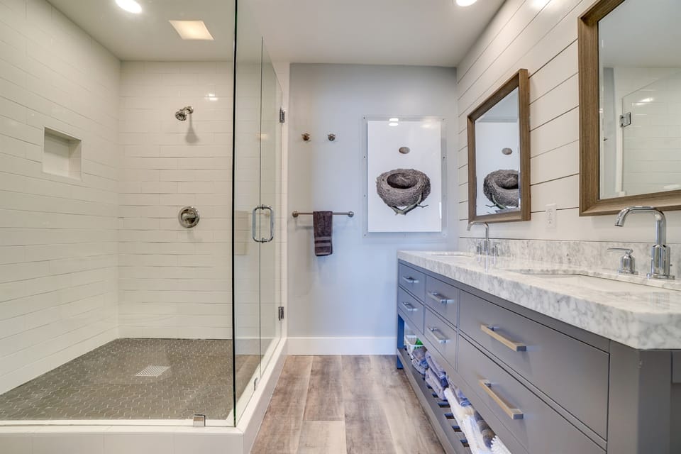 Unwind in your spa-like bathroom featuring a spacious walk-in shower, dual vanities with marble countertops, and thoughtful coastal touches.