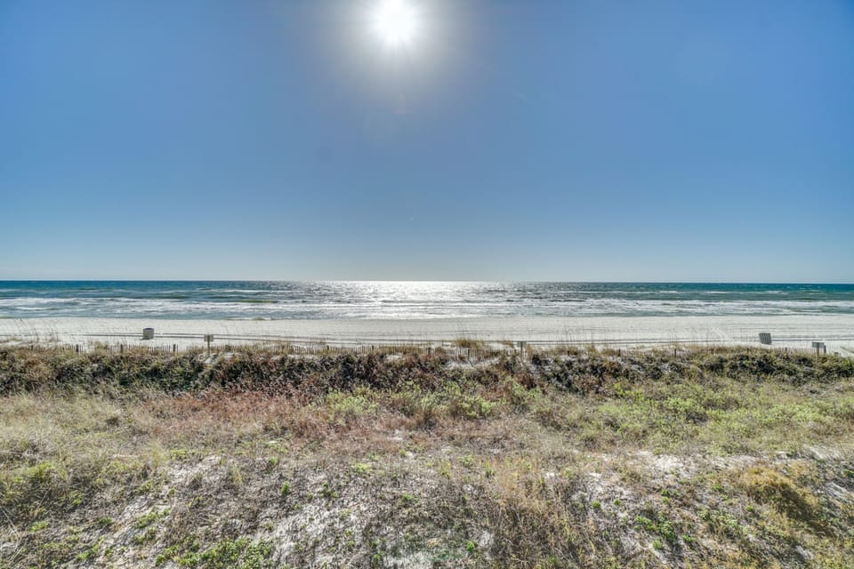 Pristine coastline stretches endlessly under brilliant sunshine, with natural dunes and protective fencing preserving this unspoiled beachfront location.