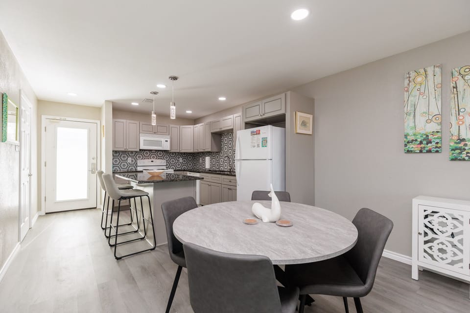 Your open-concept kitchen and dining space invites memorable meals with modern gray cabinetry, stylish pendant lighting, and a welcoming round table.