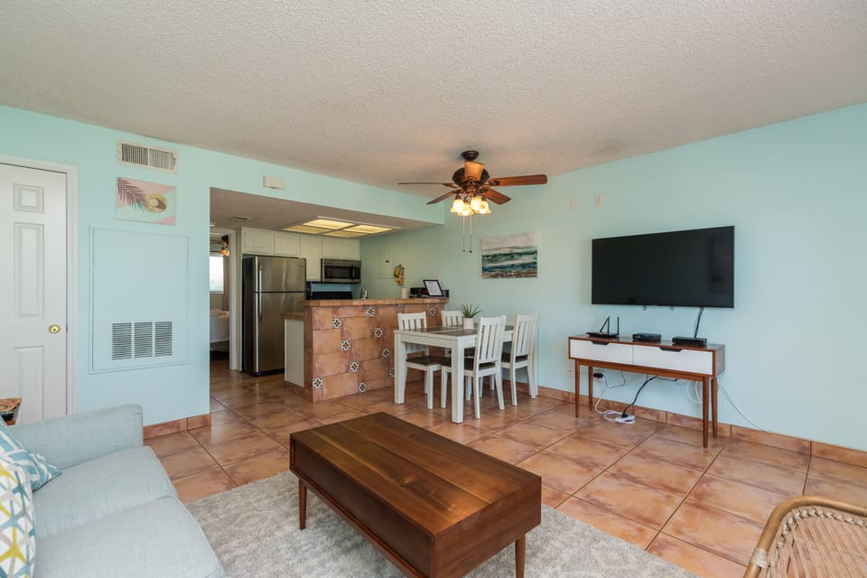 Relax in your bright, coastal-inspired living space where soft mint walls and warm tile floors create a soothing retreat for your beach getaway.