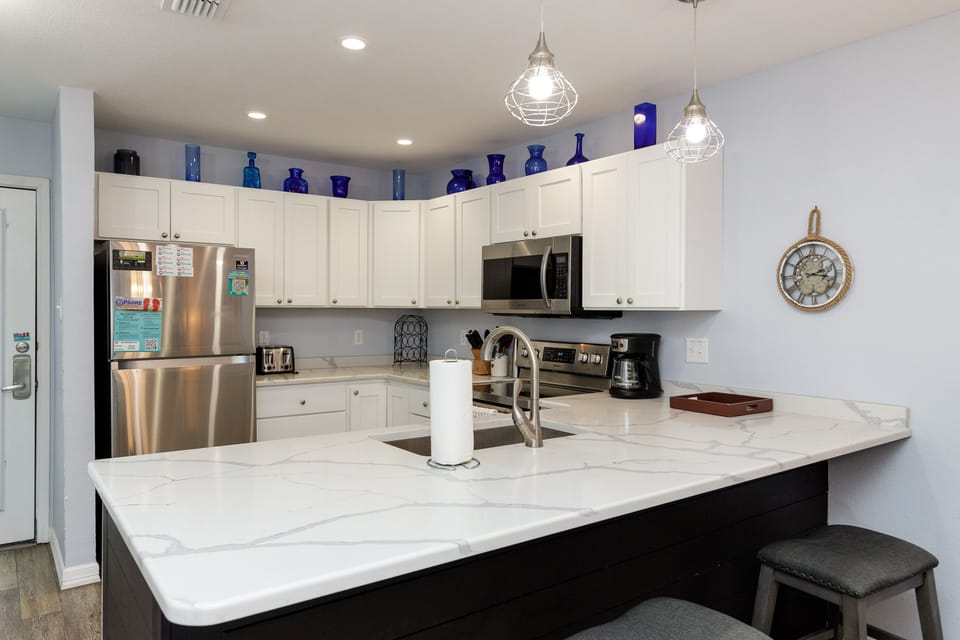 Your fully-equipped kitchen invites culinary adventures with marble countertops, stainless appliances, and charming blue bottle accents.